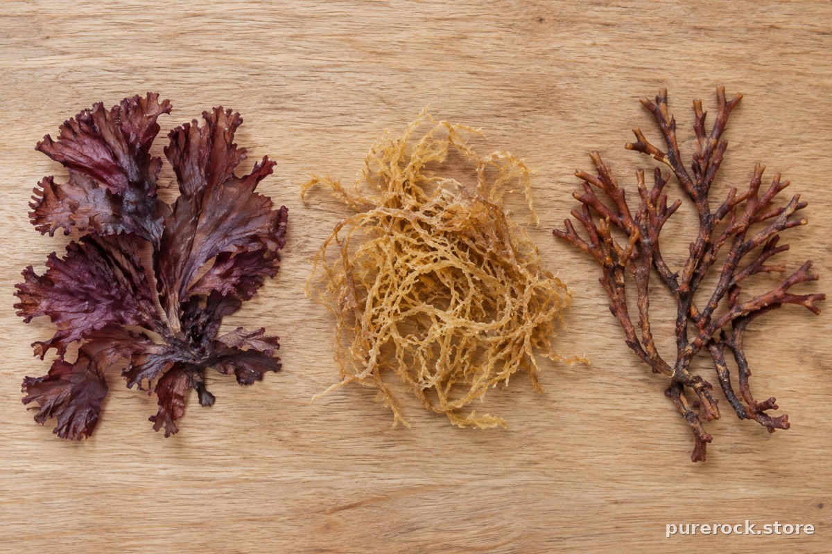 Several varieties of dried red seaweed in different colours, from pale gold to deep purple, laid out on a wooden board
