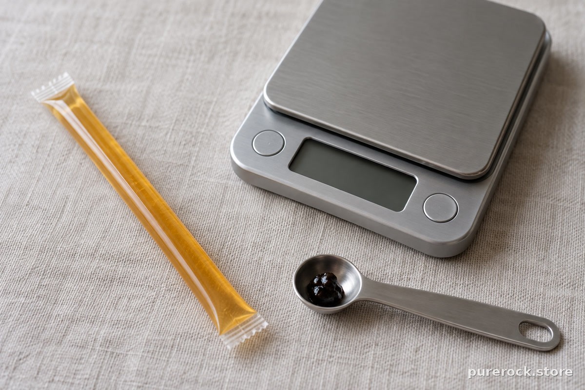 Close-up of an unbranded honey stick next to a small kitchen scale and a measuring spoon, illustrating dose-per-stick math